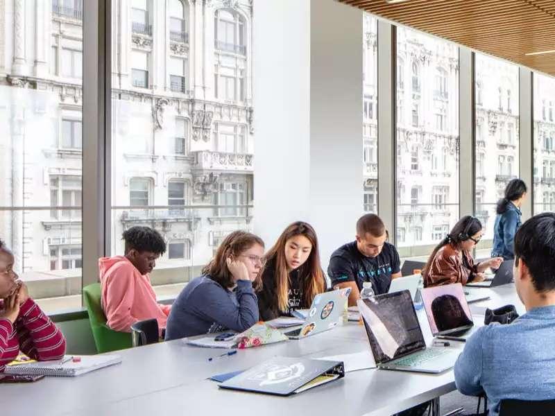 several students around a large conference table with large windows on one side